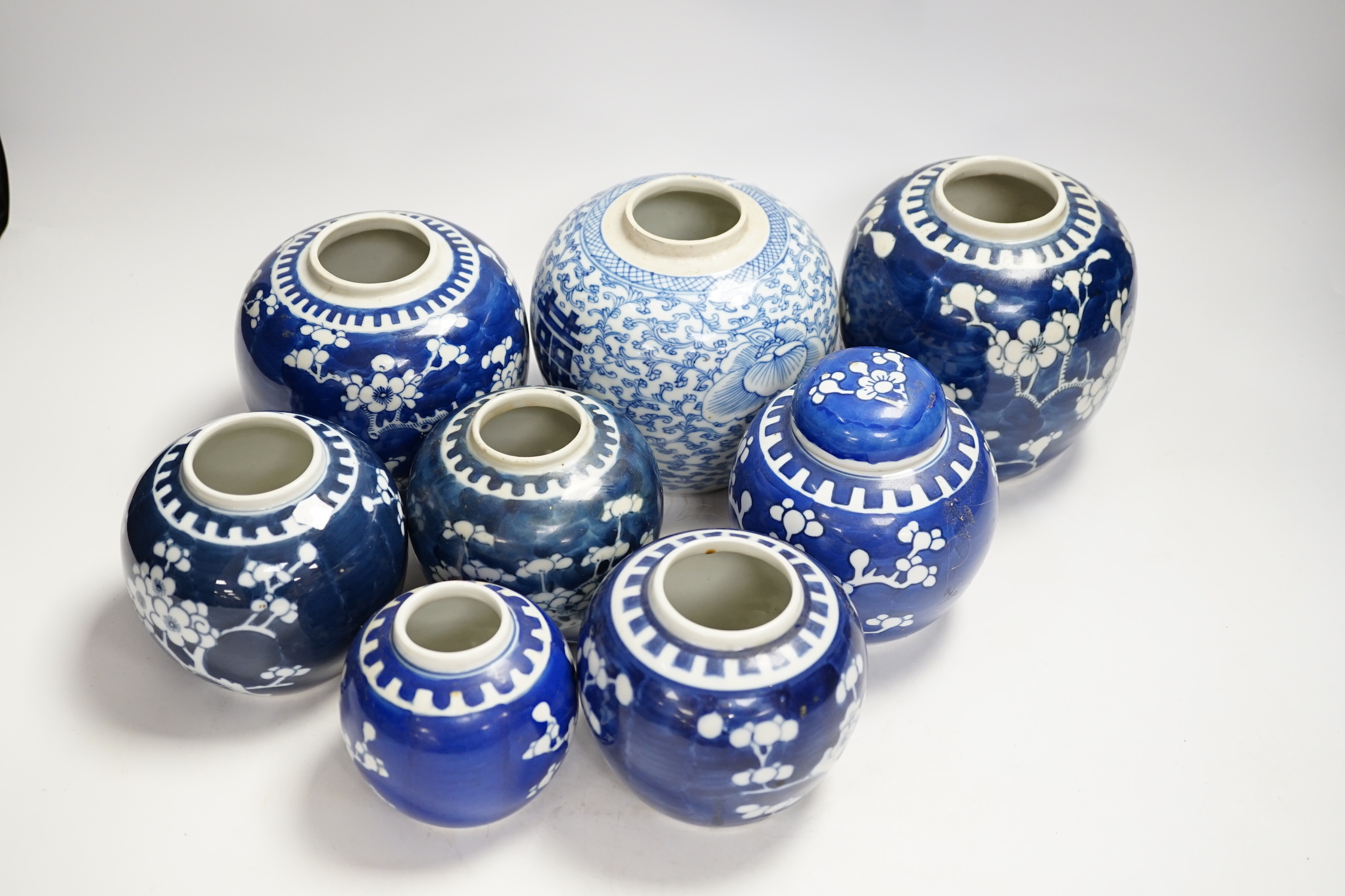 A Chinese blue and white 'shuangxi' jar, and seven blue and white 'prunus' jars and one cover, largest 14cm high (8)